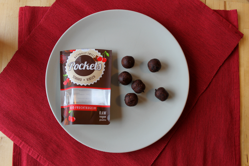 Fruchtkugel "Pockets Schoko-Kirsch" von Govinda, links Verpackung, rechts Fruchtkugeln