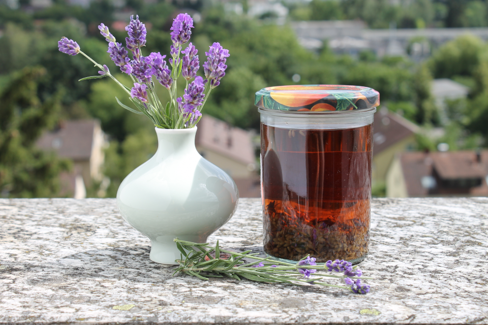 Lavendelblütentinktur im Glas mit eingelegten Lavendelblüten, Lavendelstrauß in der Vase